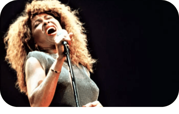 Singer, Tina Turner, singing passionately into a microphone