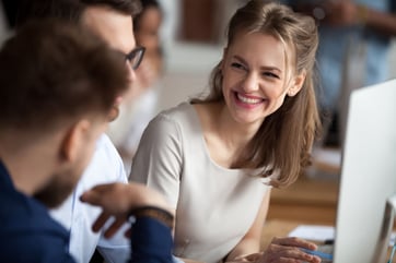 Smiling young woman talking with colleagues at shared workplace